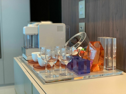 Bandeja SL Chanfreiné com copos de cristal e objetos decorativos coloridos sobre uma mesa.