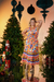 Conjunto cropped plus size com gola drapeada e saia com babados em um ambiente natalino, rodeada por árvores de Natal e enfeites.
