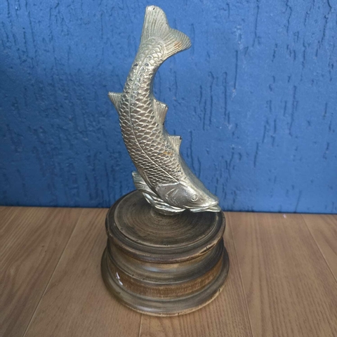 Peixe em metal prateado em base de madeira