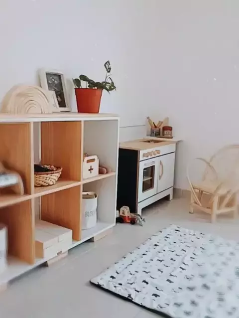 Juguetero Fran de 6 módulos en una habitación infantil, junto a una cocina de juguete y una alfombra con estampado de animales.