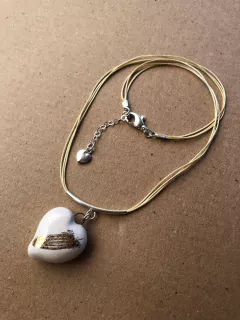 Dije corazón con pluma dorada en internet