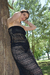 Modelo con un conjunto negro calado de playa, apoyada en un árbol, en un ambiente natural.