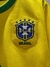 Detalle del escudo de la camiseta de Brasil "Ronaldo" para niño, con fondo amarillo y verde.