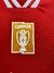 Detalle de la camiseta roja del Benfica, mostrando el logo de campeón en dorado.