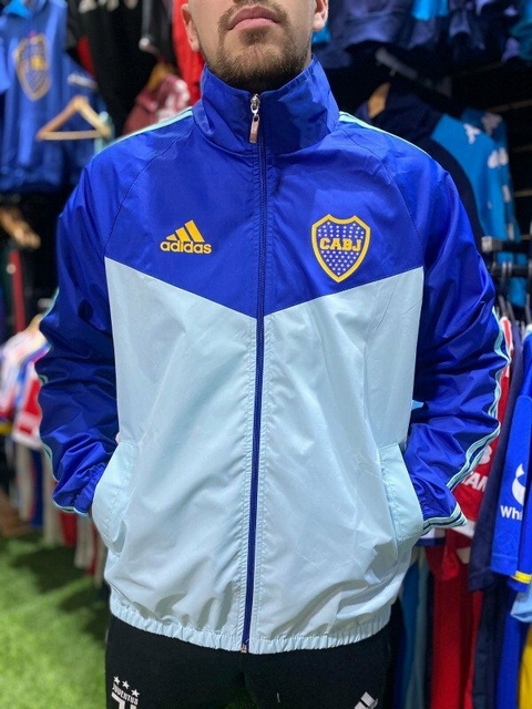 Campera rompeviento de Boca Juniors en colores azul y verde agua, con el logo del club y detalles de la marca Adidas.