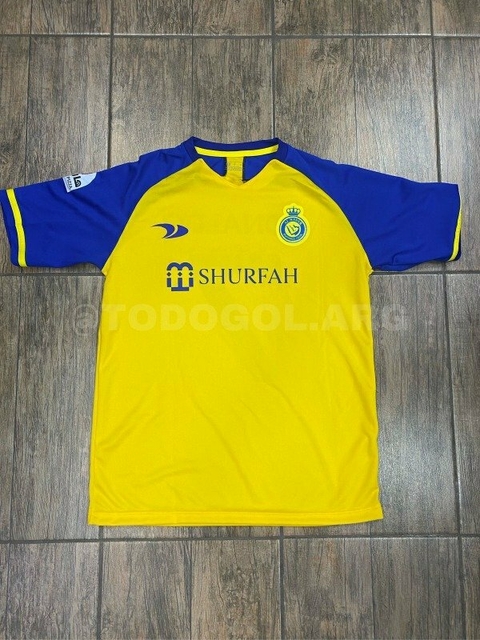 Camiseta titular del equipo Al Nassr, color amarillo y azul, con detalles del patrocinador y el escudo del club.