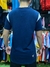 Hombre de espaldas vistiendo una remera de algodón azul con detalles en blanco, en un entorno de tienda de ropa deportiva.