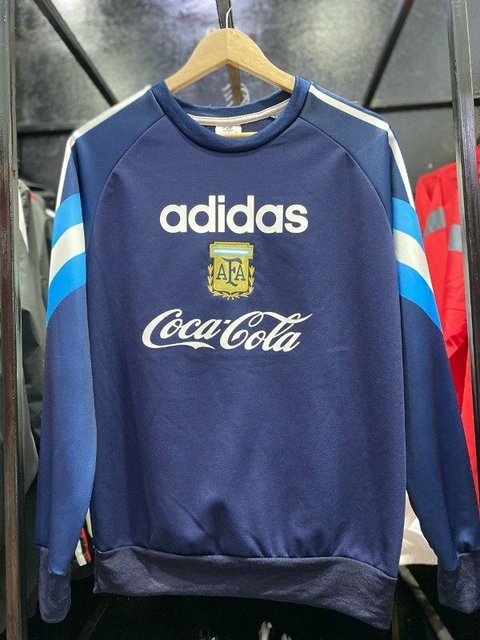 Buzo retro azul de Argentina 1996 con logos de Adidas y Coca-Cola.