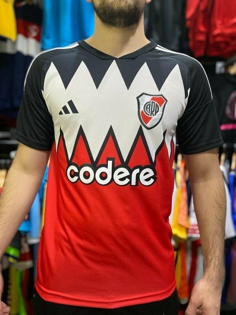 Camiseta suplente de River Plate 23/24 con diseño en rojo y negro, logo del club y patrocinador visible.