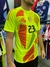 Camiseta amarilla flúor del "Dibu Martínez" con diseño geométrico y número 23, presentada en un entorno de ropa deportiva.
