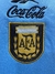 Logo bordado de la Asociación del Fútbol Argentino (AFA) en un buzo celeste de Reebok.