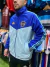 Hombre usando una campera rompeviento de Boca Juniors en colores azul y verde agua, con el logo del club.