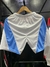 Shorts deportivos de Argentina 2024 en colores blanco y celeste, colgados de una percha.