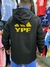 Hombre de espaldas vistiendo un rompeviento negro con el logo de YPF en amarillo, en un entorno con varias camisetas de fondo.