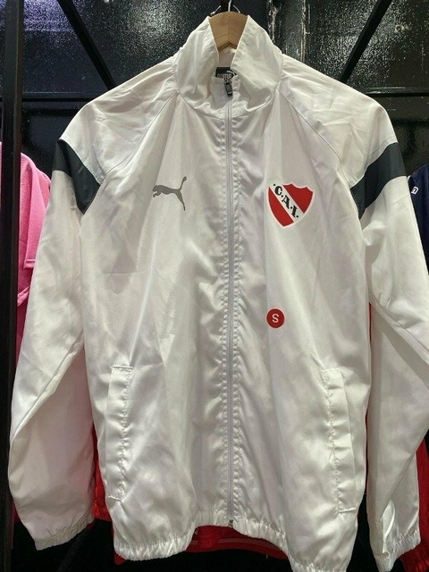 Rompeviento blanca de Independiente con logo y detalles en negro, colgado en una percha.