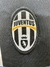 Logotipo de la camiseta retro de Juventus, con la inscripción "JUVENTUS" y un diseño de franjas verticales en blanco y negro.