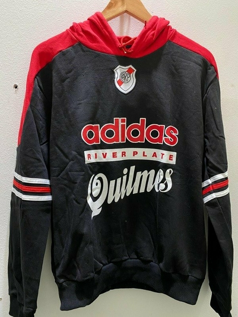 Buzo canguro retro de River Plate 1997, de color negro con detalles en rojo y logo de Adidas, presenta las inscripciones "RIVER PLATE" y "Quilmes".