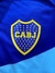 Escudo del Club Atlético Boca Juniors en una campera rompeviento de color azul con verde agua.