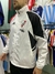 Rompeviento blanco de River Plate con detalles en rojo y negro, modelo utilizado por un hombre en una tienda de ropa deportiva.