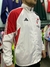 Rompeviento blanco de River Plate con detalles rojos y negros, modelo de la marca Adidas, visto de perfil.