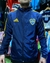 Rompeviento impermeable de Boca Juniors, color azul marino con detalles en amarillo, modelo de Adidas, visto de frente.