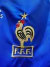 Logo bordado de la selección de fútbol de Francia en una camiseta azul, mostrando un gallo y una estrella dorada.