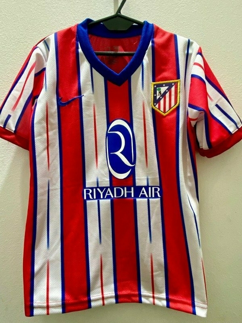 Camiseta del Atlético Madrid con diseño a rayas rojas y blancas, talla niño, con el logo del club y patrocinador.