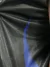 Primer plano de un rompeviento negro con detalles en azul, mostrando la textura de la tela.