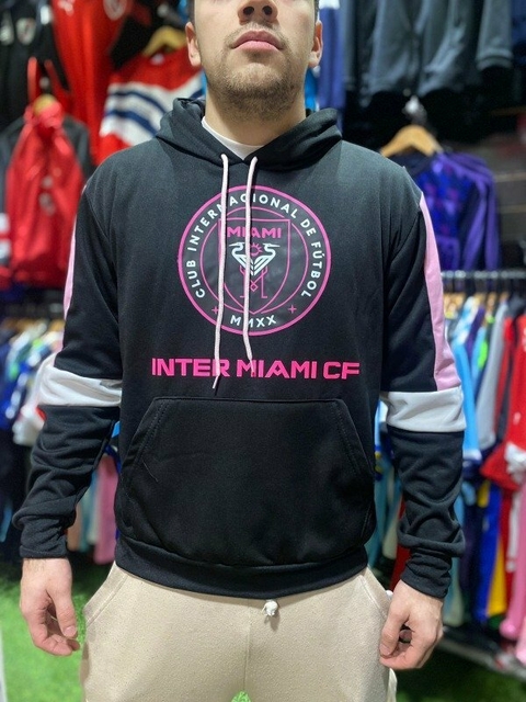 Hombre usando un buzo negro con el logo del Inter de Miami en el pecho y detalles en rosa.