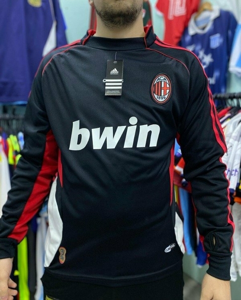 Buzo retro del AC Milan 2006, de color negro con detalles en rojo y el logo de Bwin en el frente.