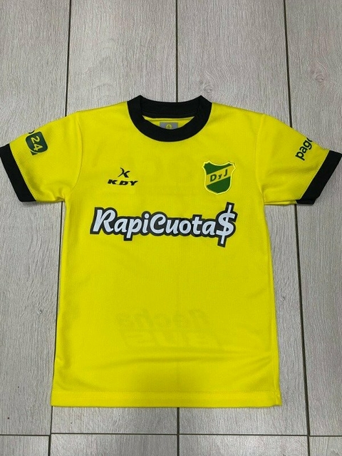 Camiseta amarilla de Defensa y Justicia para niños, con el logo del club y el patrocinador "RapiCuota$".