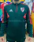 Buzo de entrenamiento de River Plate con medio cierre y diseño en verde y rojo.
