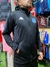 Hombre usando una campera deportiva de Racing, color negro, con detalles en azul y logo de Kappa.