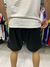 Vista trasera de shorts negros del River Plate con cierres, usados por una persona que lleva una camiseta blanca.