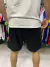 Vista trasera de shorts negros del River Plate con cierres, usados por una persona que lleva una camiseta blanca.