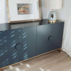 Vista de frente del mueble Vajillero color azul, que tiene cuatro puertas con tiradores decorados, y cuatro patas metálicas.
