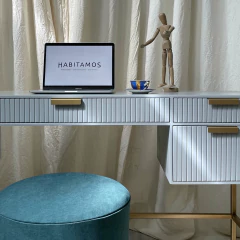 Escritorio moderno con computadora portátil, un maniquí de madera y una taza sobre la mesa.
