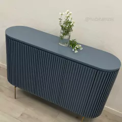 Mueble de estilo moderno en color azul con detalles en relieve, decorado con un jarrón transparente y flores.