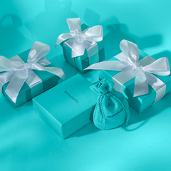 Caixas de presente da Tiffany & Co. com laços brancos em um fundo azul-turquesa.