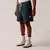 Modelo usando shorts de moletom Fila na cor branca com detalhes em azul, acompanhado de tênis claros e meias listradas.