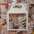 Caja de regalo blanca con una taza de diseño y chocolates, decorada con cintas y etiquetas, presentada en un entorno festivo.