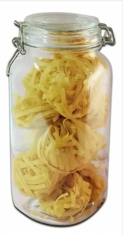 Frasco de vidrio hermético grande lleno de tiras amarillas de pasta.