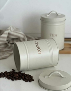 Lata decorativa para café, con granos de café a su alrededor.