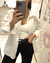 Mujer posando frente a un espejo la Camisa Lorena blanca de poplin rayado, con manga larga, bolsillo en el pecho y corte más largo atrás