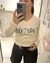Remera Tokio manga larga beige con estampado "Pura Vida" en el frente, usada por mujer que se toma una selfie frente a un espejo