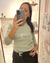 Mujer sacándose una selfie y mostrando una remera verde modelo Tokio de manga larga con el texto "Respira suelta perdona".