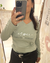 Mujer sacándose una selfie y mostrando una remera verde modelo Tokio de manga larga con el texto "Respira suelta perdona".