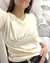 Remera Tokio de mujer color beige con estampa "vida" en letra cursiva negra, usada por una mujer que se está sacando una selfie frente a un espejo