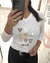 Mujer usando una remera blanca Tokio con estampa de corazones multicolores y texto "You & Me", tomada en un espejo