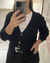 Mujer usando saco tejido color negro con botones simil madera y escote en V, con detalles calados.